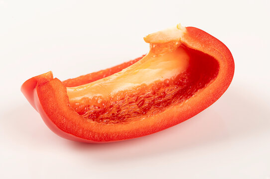 Macro shot of  single, vibrant red bell pepper slice. Showing juicy texture and fresh details, isolated on  white background. Perfect for healthy food and cooking concepts.