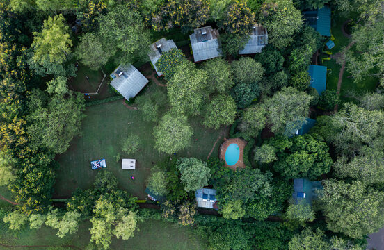 Aerial view of Sagana resort nestled in lush forest with cabins, a swimming pool, and tents on a green lawn in Sagana, Kirinyaga County, Kenya.