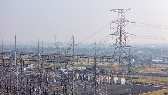 Aerial view of a high-voltage electrical substation with transmission towers and power lines set against a rural landscape in Klaten, Central Java, Indonesia.