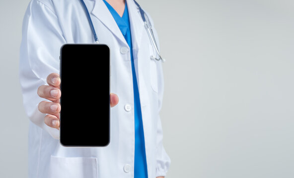 Doctor white coat holding smartphone mockup with blank screen for healthcare app, telemedicine, medical technology, digital health, online consultation, mobile application promotion, and copy space.