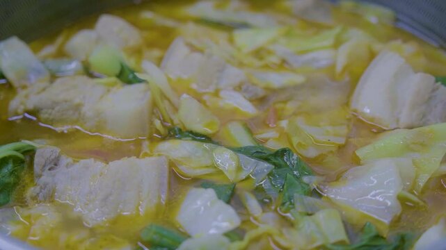 Cooking Filipino Pochero with pork, vegetables, and broth in a pot on a stove