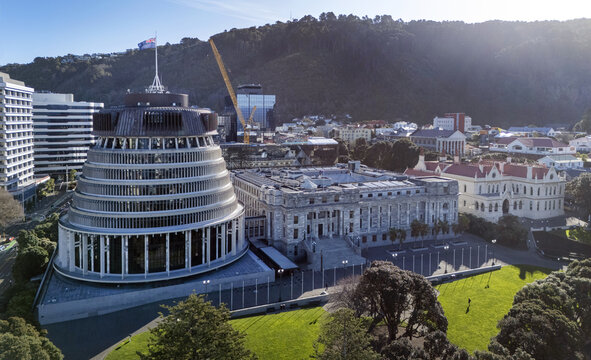 Aerial view of the Beehive and Parliament House surrounded by lush green lawns and urban buildings in Wellington, Wellington Region, New Zealand.