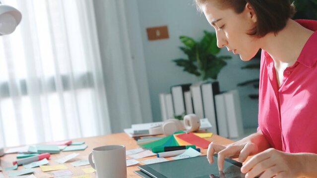 Top view of designer writing idea on colorful sticky notes while sitting at meeting table with tablet display logo design. Professional business woman looking design and making a decision. Symposium.