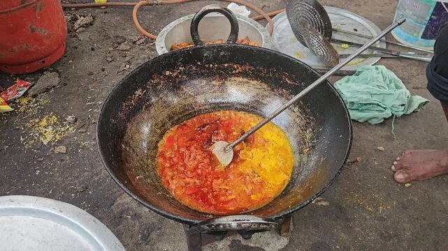 Traditional Indian Cooking in Large Iron Wok, Spicy Curry Masala Being Prepared in Outdoor Kitchen, Authentic Indian Food Preparation with Oil, Tomato and Turmeric, Street Food and Cuisine