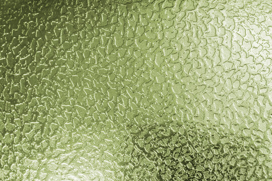 Abstract green silver metallic background featuring a shiny, reflective surface with an irregular hammered texture, subtle highlights, and soft shadows, creating a modern industrial background.