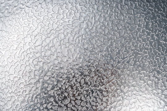 Abstract silver metallic background featuring a shiny, reflective surface with an irregular hammered texture, subtle highlights, and soft shadows, creating a modern industrial background.