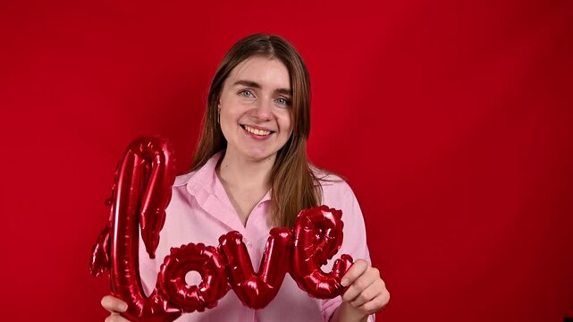 Happy Woman Feeling Love and Joy on Valentines Day. Love sign balloon, studio footage with copy space 