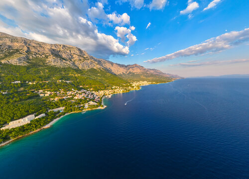 Aerial view of the coastal town of Brela nestled between the Adriatic Sea and Biokovo mountains, with pine forests and rocky beaches in Brela, Split-Dalmatia County, Croatia.