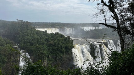 Majestic Iguazu Falls in Brazil showcasing multiple cascades surrounded by lush green rainforest under a cloudy sky © Felippe Lopes