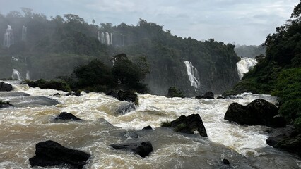 Majestic Iguazu Falls in Brazil with powerful cascades and lush green rainforest under a cloudy sky © Felippe Lopes