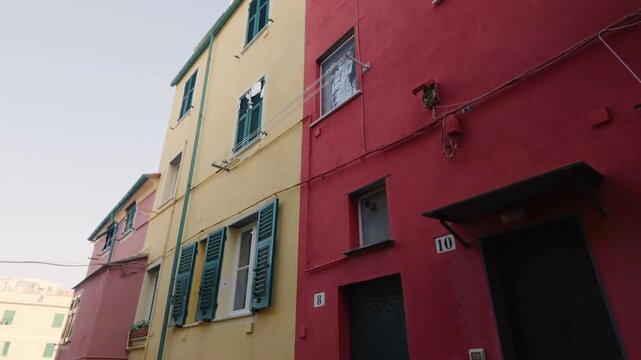 Colorful traditional houses with green shutters in a narrow street, daytime view