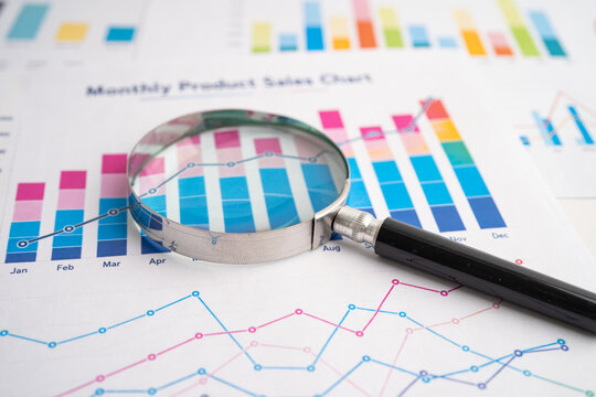 Magnifying glass on spreadsheet and graph paper.