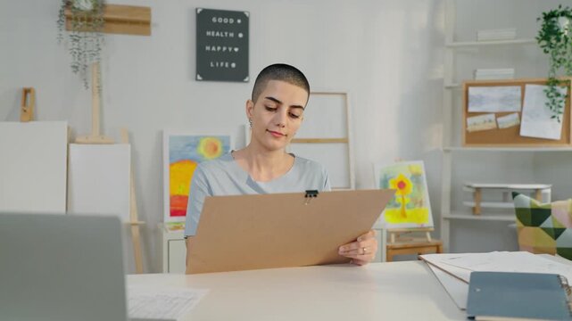 Caucasian female artist painting artwork on canvas frame at home studio.