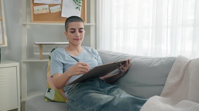 Caucasian female artist painting artwork on canvas frame at home studio.