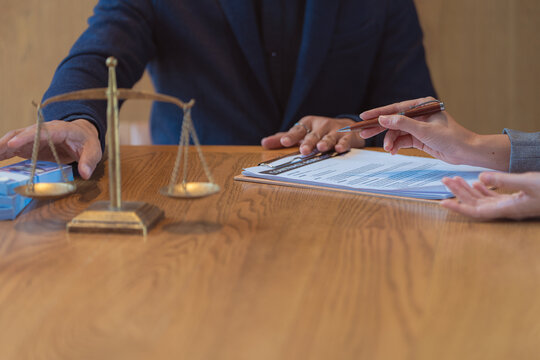 A lawyer is explaining real estate law to a client, with a house model and a judge's gavel placed nearby&mdash;a close-up shot focusing on home mortgages and property division.
