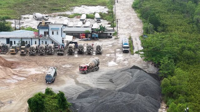 Aerial view of cement mixer trucks parked in a row and piles of raw materials for cement production