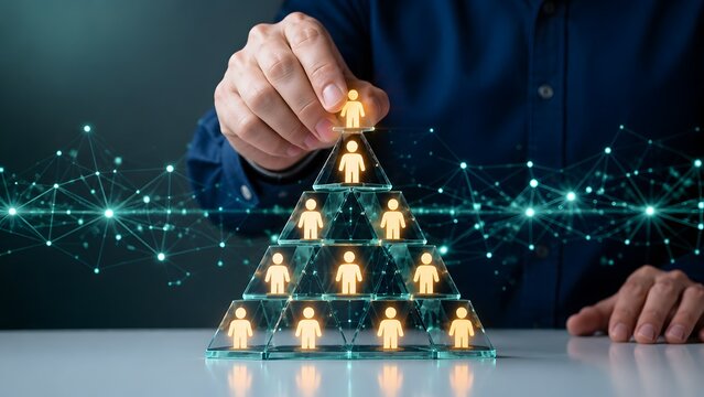 Businessman hand placing top glowing person icon onto glass pyramid structure with digital nodes. Concept of corporate leadership and business strategy.