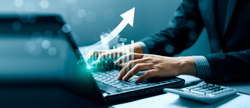 Business financial forecast concept with professional typing on laptop beside calculator showing rising arrow chart, yearly growth projection, revenue performance and investment planning
