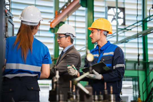 Engineers and workers discussing production process in factory, Industrial team checking machinery and operations in manufacturing plant, Professional supervisors and worker talking in a workshop