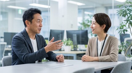 Obraz premium Japanese man and woman in business attire discussing at a modern office table