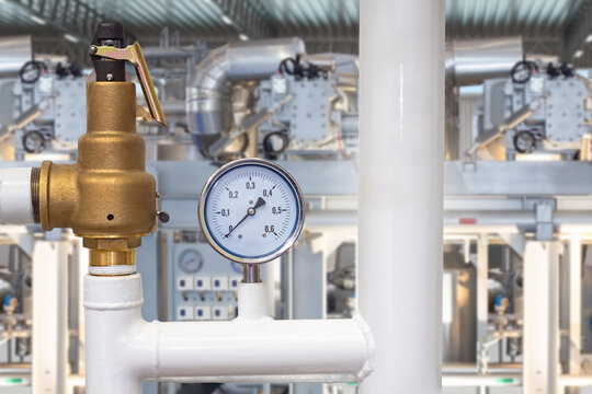 Industrial plant, Pressure control. Safety valve and pressure gauge monitor an industrial piping system, ensuring equipment protection, process safety and reliable plant operation.