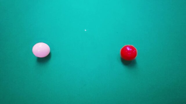 A slow-motion, side-view shot of a snooker player executing a screw back shot, striking the white cue ball to hit the red ball on a green table.