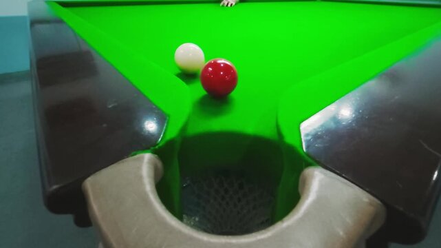 High-angle cinematic slow-motion footage of a snooker shot. The white cue ball hits the red ball towards the pocket, but it fails to drop in.