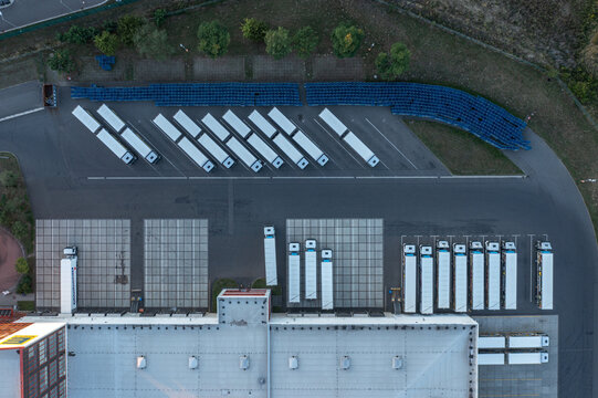 Aerial view of Edeka Zentrale Handel Und Produktion Gmbh logistics facility with rows of semi-truck trailers parked at loading docks in Mittenwalde, Brandenburg, Germany.