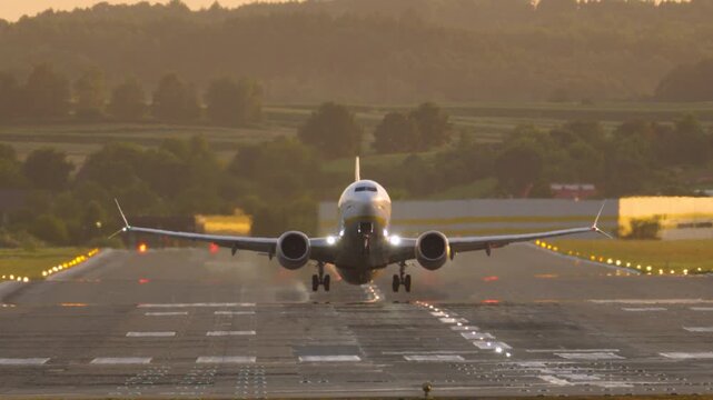 Aerial view of a commercial airplane taxiing on the runway at sunset in Krakow, Poland.