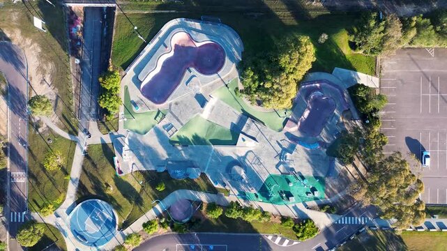 Drone aerial landscape of public skatepark facility with ramps halfpipes and concrete bowls surrounded by a carpark and basketball court at Bateau Bay Central Coast NSW Australia sports and leisure