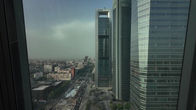High-rise view along a major Madrid avenue between modern glass office towers and the surrounding urban skyline.