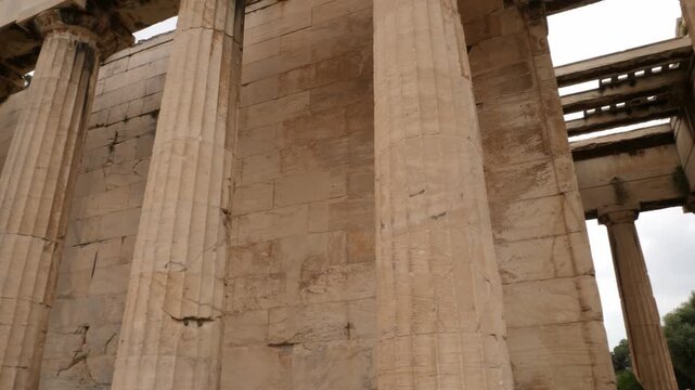 Slow horizontal panning shot along the preserved Doric marble columns and wall of the ancient Temple of Hephaestus in Ancient Agora, Athens, Greece, showing classical architectural details.