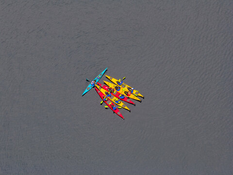 Aerial view of colorful kayaks with people paddling on calm water in Valldal, More og Romsdal, Norway.
