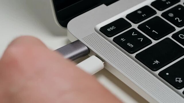 Laptop Charging Cable Connected to Smartphone USB Port on White Desk Close Up