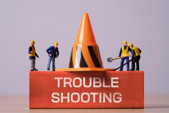 Miniature workers and traffic cone with troubleshooting for problem solving, maintenance repair, technical support, error diagnosis by teamwork and fixing operational issues or business challenges.