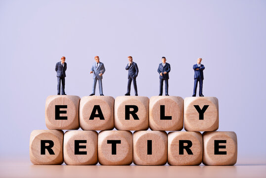 Early retirement concept with miniature business people standing on wooden letter blocks representing financial freedom, retirement planning, savings, investment strategy and career exit goals.