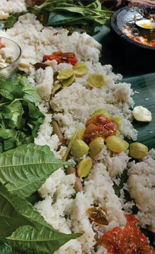 Sundanese traditional communal dining Liwetan with white rice, chili paste, and green herbs.