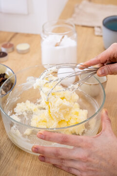 Bakery work. Mixing process. Female chef hand whisking butter sugar ingredients for homemade dough in glass bowl on kitchen countertop.