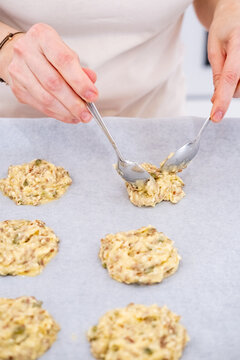 Pastry preparation. Baking cookies. Chef woman hand placing dough portion with oat flakes raisins on white parchment kitchen paper tray.