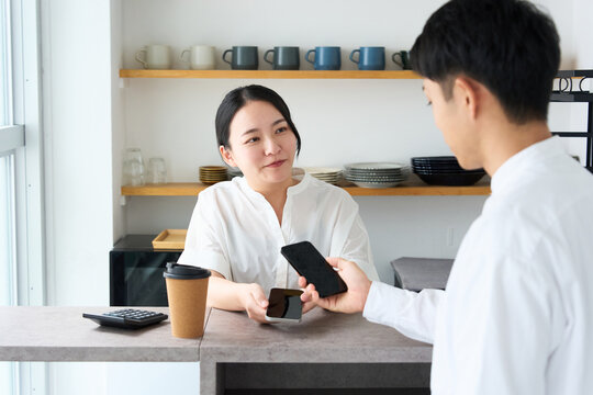 Young Japanese Woman Making Cashless Payment with Smartphone at Cafe Counter