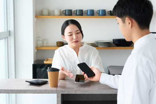 Young Japanese Woman Making Cashless Payment with Smartphone at Cafe Counter