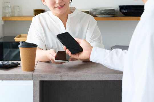 Young Japanese Woman Making Cashless Payment with Smartphone at Cafe Counter