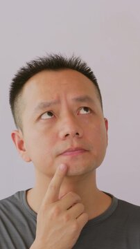 Vertical video: Thinking idea and Asian man in studio with question doubt or decision for career development choice. Man thinking quesiton.