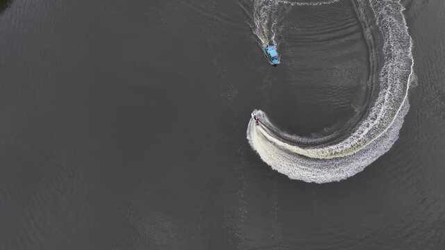 Speed boat overtaking a smaller boat leaving a curving wake on the water