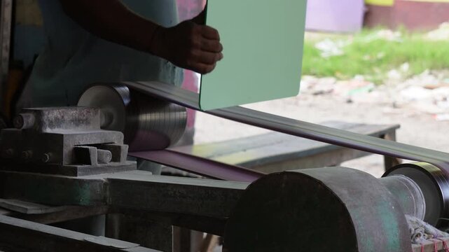 Worker polishing mirror glass with industrial belt sander