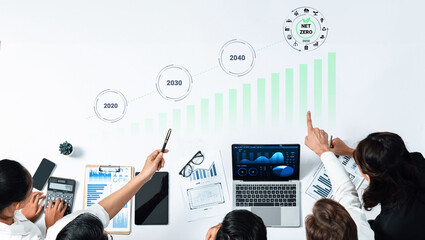 Professionals engage in data analysis to assess strategies for achieving net zero by 2040, utilizing charts and technology in a collaborative office environment. Gantry © InfiniteFlow