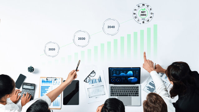 Professionals engage in data analysis to assess strategies for achieving net zero by 2040, utilizing charts and technology in a collaborative office environment. Gantry