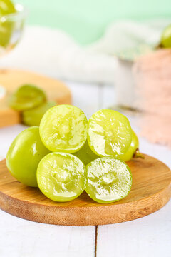 Fresh Green Seedless Grapes Cut in Half on Wooden Board Showing Juicy Interior