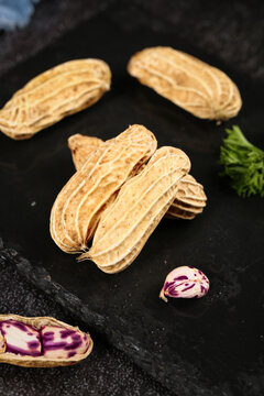 Fresh Yunnan Plateau Peanuts in Shells on Dark Slate - Purple and Beige Groundnuts