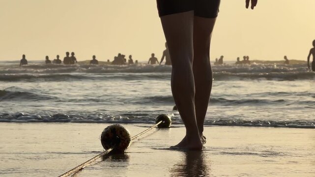 Close up of Buoys on Safety Rope at sandy Beach Shoreline with people in the water at sunset